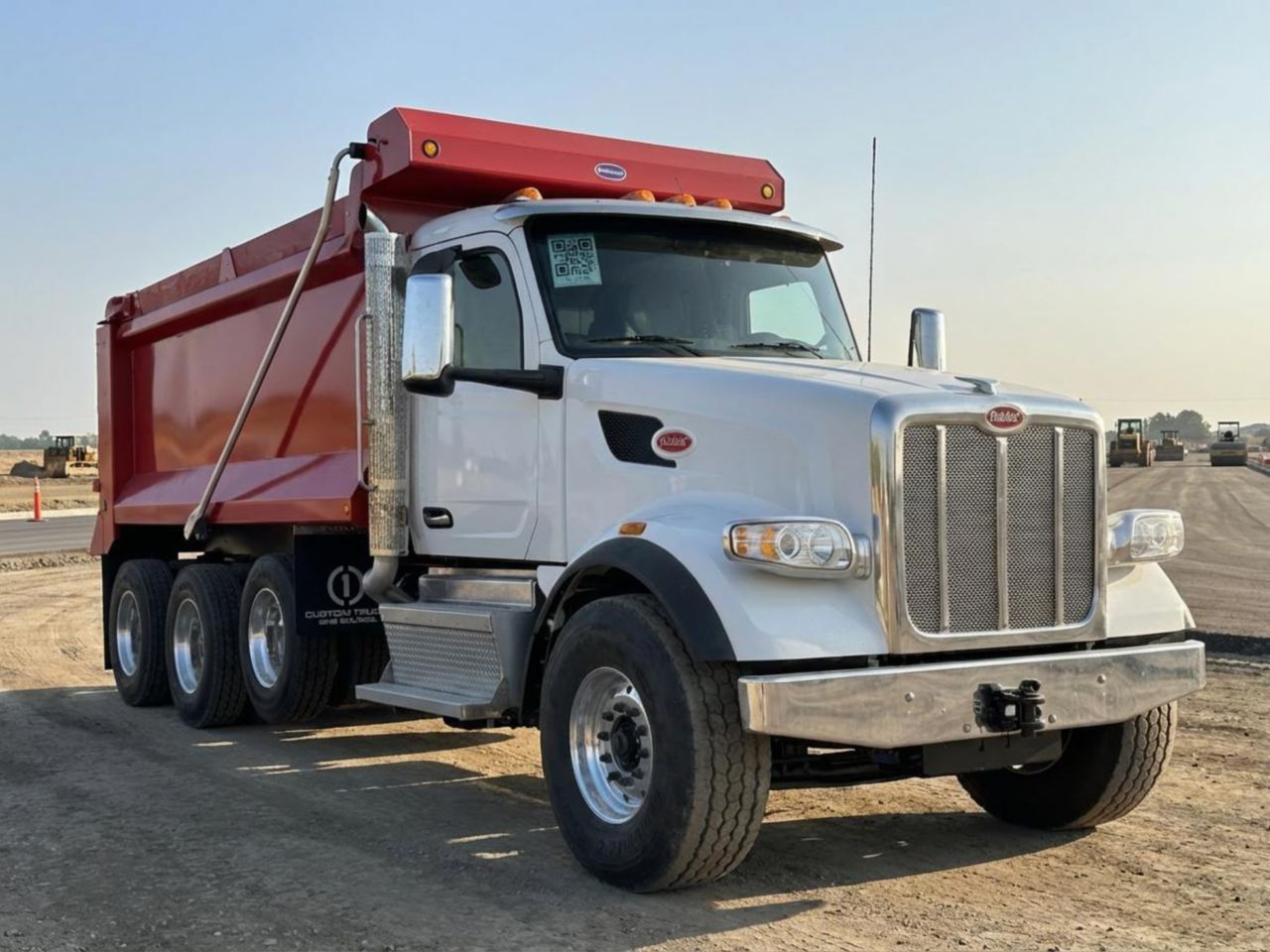 Dump truck on paving job site with road rollers