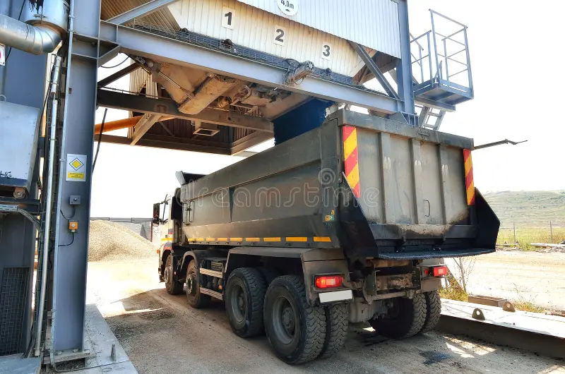 Dump truck loading under batch plant chute for concrete work